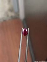 Ruby held in tweezers showing table and crown facets