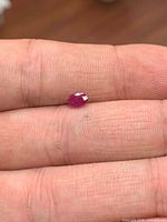 Ruby gemstone on fingertip showing size and oval faceting