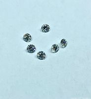 Six small round diamonds on white surface