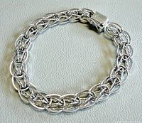 Full view of sterling silver bracelet laid flat showing interwoven links and clasp