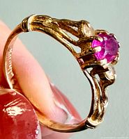 Side view of ring showing ruby, prongs and ornate shoulder design