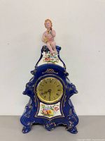 Full view showing cobalt blue porcelain clock with cherub figure and floral panels