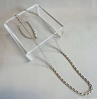 Full view of silver chain displayed on clear stand