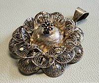 Full view of silver filigree flower pendant showing front design and bale