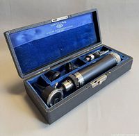 Open case showing ophthalmoscope handle, head and three attachments in blue velvet interior