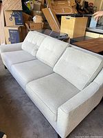 Front view of beige three-seat sofa with cushions and wood legs
