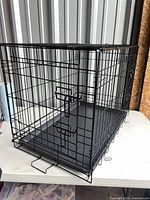 Front and side view of black wire dog crate showing double door and overall condition