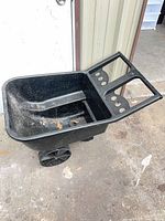 Oblique view of black plastic wheelbarrow tub showing interior and molded front section