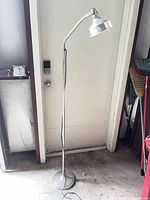 Full view of chrome gooseneck floor lamp standing on weighted base