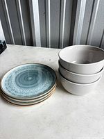 Stack of six blue patterned plates beside three white bowls