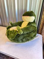 Front angled view of frog plush rocker on table