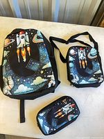 Front view of backpack, lunch bag and pencil case showing matching space print