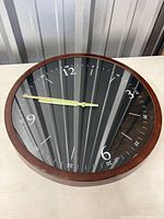 Front view of round wood wall clock showing dial and hands