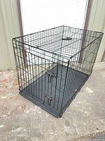 Overall view of black metal wire dog crate with plastic tray inserted