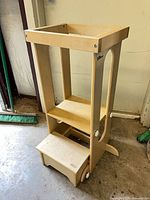 Full view of wooden learning tower showing platform, step and wheels