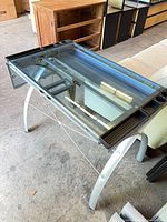 angled view showing glass top, metal legs, black trays