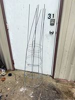 Two tall wire tomato cages leaning against a door