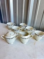 Full seven-piece set displayed: creamer, lidded sugar bowl, five teacups