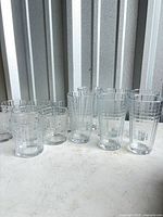Group of 6 tall tumblers and 7 short rocks glasses on surface