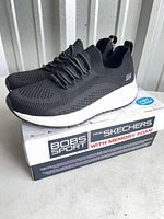 Side view of both sneakers on original box