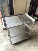 Full view of stainless steel cart showing three shelves and casters