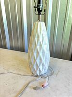 Full view of white ceramic lamp base showing geometric pattern and clear cord
