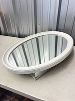 Angled view of closed oval mirror cabinet