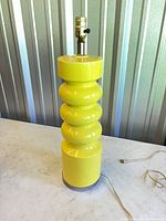 Full view of yellow ribbed ceramic table lamp with cord
