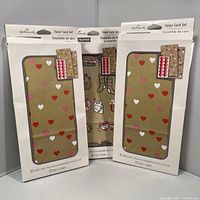 Front view of three packaged Hallmark favor sack sets showing heart design through window