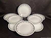 Eight matching Corelle plates displayed on black background