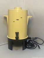 Front view of assembled percolator showing exterior, spigot, base and cord