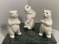 Front view of three white porcelain animal figurines: two bears and one elephant