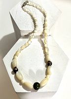 full view of necklace showing shell beads, green serpentine beads, and clasp