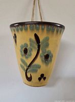 Front view of conical glazed Polish pottery wall planter with floral motif