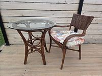 Full view of round rattan table with glass top and matching chair on deck