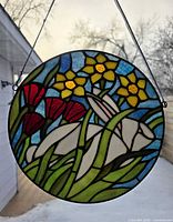 Full view of round stained glass panel hanging outdoors