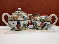 Teapot and creamer front view showing rooster decoration and handles