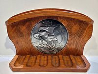 front view of wooden pipe rack with ship medallion and lower grooves