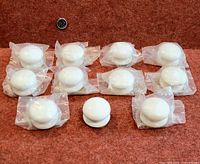 Ten white porcelain cabinet knobs, nine in plastic wrap, one unwrapped