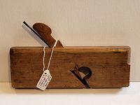Side view of complete wooden molding plane with wedge and hang tag