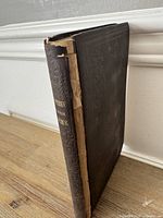Angled view of book showing spine loss and board condition