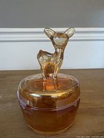 Full front view of amber carnival glass candy dish with fawn lid