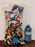Full view of sealed bag of LEGO pieces beside 1-litre water bottle for size reference