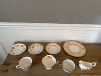 Seven pieces on table: three saucers, oval plate, three teacups