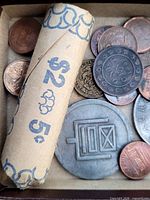 Top view of box showing nickel roll, assorted copper US cents, grey tokens and Sun Yat-sen coin