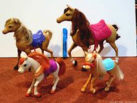 Group of four Barbie horses with saddles visible