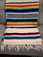 Full view of blanket laid on couch showing entire pattern and fringe