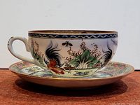 Side view of cup resting on saucer showing exterior decoration