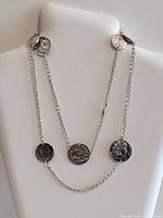 Full view of necklace on display form showing chain and coin medallions