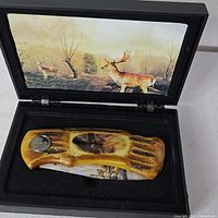 Knife in open presentation box showing handle and interior deer artwork